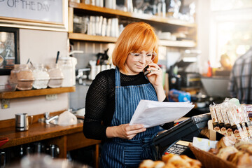 Woman, phone call and shop owner in restaurant with documents, thinking and reading for price,...