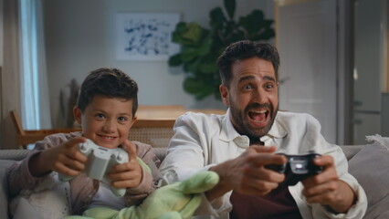 Excited gamers family playing video game at home closeup. Father son at house