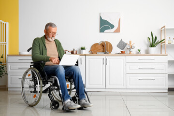 Senior man in wheelchair using laptop at home