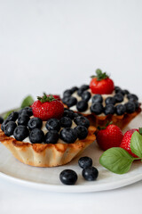 A tempting assortment of delectable blueberry and cream tartlets, beautifully garnished with fresh strawberries.