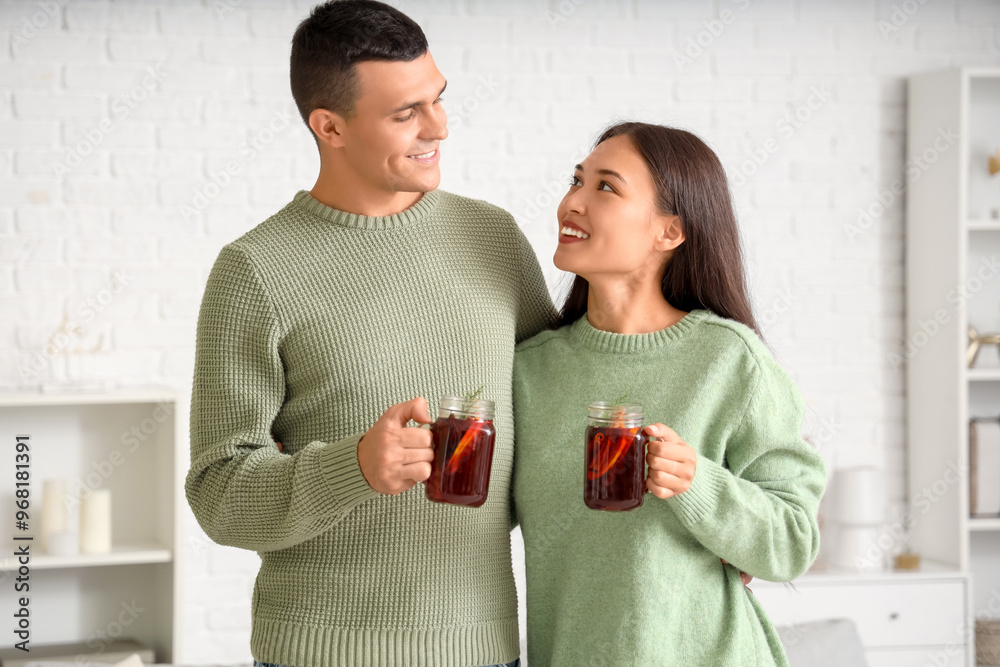 Sticker happy couple with glasses of warm mulled wine in living room