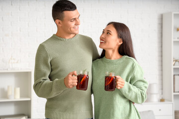 Happy couple with glasses of warm mulled wine in living room