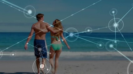 Animation of network of connections over caucasian couple walking on beach - Powered by Adobe