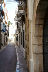 A narrow street with a view of the sea in Sitges, a beautiful resort village in Catalonia, Spain