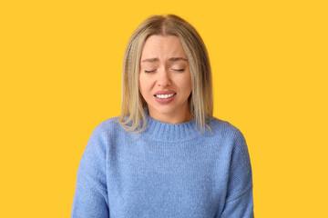 Young woman feeling awkward on yellow background