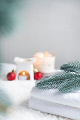 Fresh white towels with fir branch, candles and Christmas decorations. Skin care and body care. SPA massage or beauty salon, relaxation and self care in Christmas or New Year variant. Copy space.