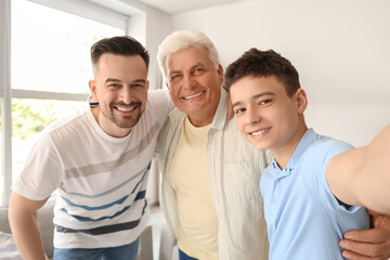 Obraz premium Teenage boy with his dad and grandfather taking selfie at home