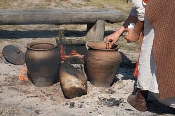 The herbalist dyes fabrics using natural methods. Large clay pots with plants to dyeing in...