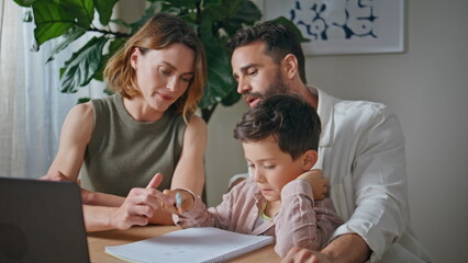 Closeup family doing homework together in living room. Small child and parents