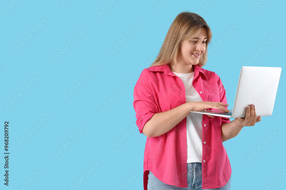 Wall mural young woman using laptop on blue background