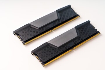 A pair of black and gray computer memory ram sticks isolated on a white background with a modern and sleek design and a textured surface. The ram sticks are aligned horizontally next to each other.