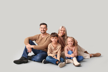Happy family with children in winter clothes sitting on grey background
