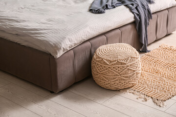 Stylish modern bed with fresh clean bedding and wicker ottoman in room at home, closeup