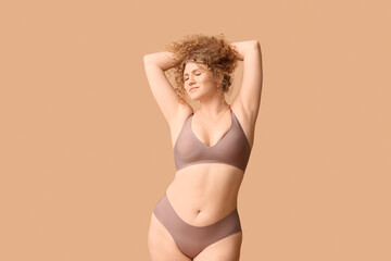 Beautiful young body positive woman in trendy underwear on beige background