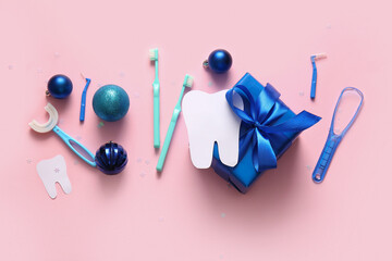 Composition with Christmas gift, dentist's tools and decorations on pink background