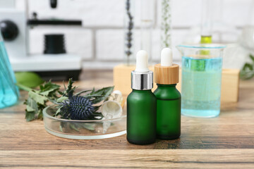Laboratory glassware and microscope with ingredients for preparing natural cosmetics on brown wooden table near white brick wall