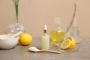 Laboratory glassware with ingredients and samples for preparing natural cosmetics on grey table near beige wall