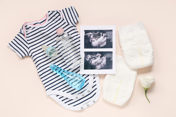 Composition with baby clothes, sonogram images, diapers and bottles of cosmetic products on pink background