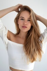 Naklejka premium Female with blonde long hair posing in white top on white background