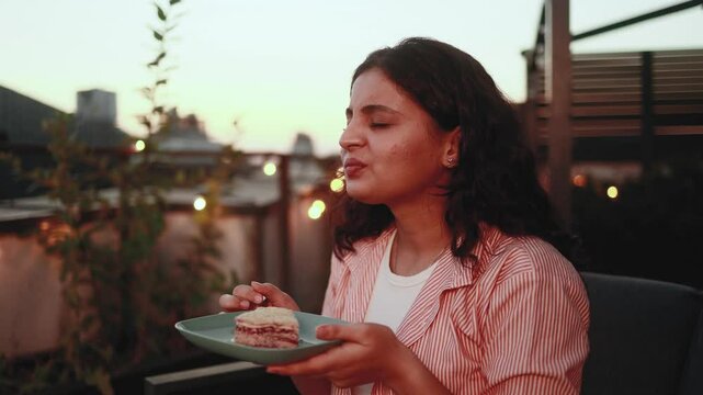 Portrait of young indian woman eating cake sweets and having toothache sitting at couch at home terrace Sad female feeling pain in tooth because caries gum disease or sensitive teeth indoors