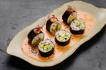 Sushi rolls on spicy sauce garnished with sesame and chili threads for an exquisite presentation