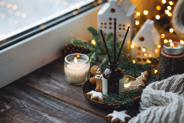 Christmas home aromatherapy. Aroma diffuser with pine extract, organic essential oil, cedar and spruce cone, cinnamon, anise, vanilla scent, candles, wooden table. Cozy atmosphere, winter inspiration