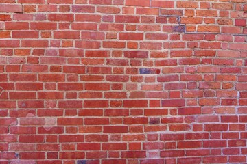 This high-quality photo showcases a red brick wall with a rough texture, featuring various shades from light to dark red. Cracks and chips add character, making it ideal for backgrounds.