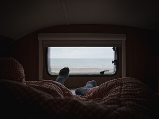 Lying on the motor home bed in the morning covered with the blanket and watching sea views