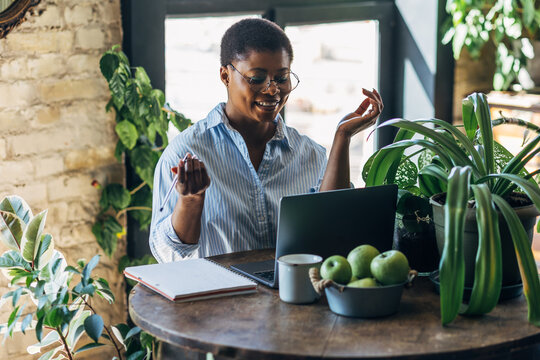 Cheerful healthy African American woman with laptop at home or in modern green office. Concept of video call, freelance job, studying remotely, learning, teaching languages, international education