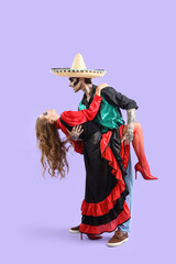 Young happy couple dressed for Mexico's Day of the Dead (El Dia de Muertos) dancing on purple background