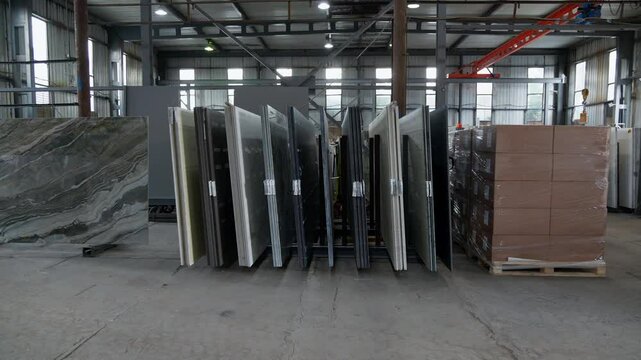 Colorful quartz and porcelain tile stone slab are standing in the factory warehouse. Kitchens and bathrooms countertop selection. Granite slabs are prepared for sale in store yard