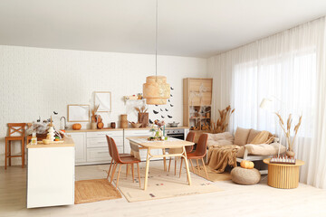 Interior of kitchen decorated for Halloween with white counters, sofa and dining table
