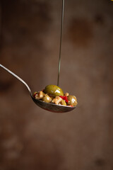 Close-up of Green Olives with Garlic and chili on a Spoon, olive oil drizzling on olives Rustic