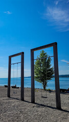 Two giant swings on the beach, on the bank of the blue lake or sea. Place for rest and entertainment.