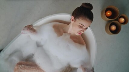 Lady enjoy bubble bath in luxury bathroom with aroma candles closeup top view. T