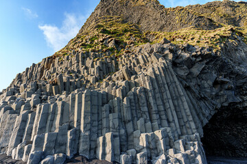 The dramatic Reynisfjara Beach features black volcanic sands and towering basalt sea stacks rising...