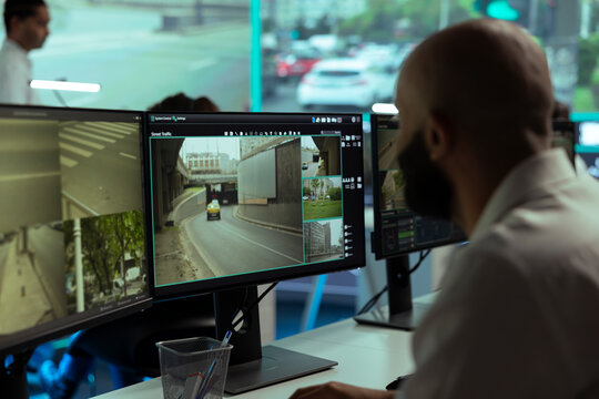 Employee supervising traffic via CCTV surveillance footage around the city, looking at video from radar system at stop lights. Working with public security cameras for street safety.