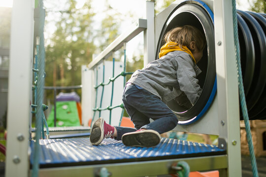 Cute toddler boy having fun on a playground outdoors on warm autumn day.