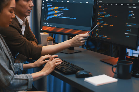 IT developers discussing with point to intelligent website development coder system running data online two screens information technology at neon light room at modern office. Infobahn.