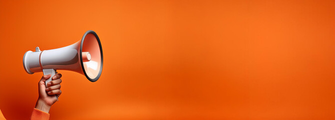 Hand holding a megaphone announces sales and discounts, on a vibrant orange background. Marketing and commercial concept banner with copy space, 