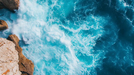 Aerial view of ocean waves meeting rocky cliffs, dynamic movement of water, vibrant sea foam, dramatic coastal landscape