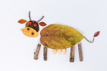 Creative piece of art made from natural materials featuring animal figure, cow crafted from leaves,...