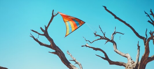 A vibrant, colorful kite stuck in the barren branches of a dead tree