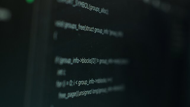 Extreme close up shot of hacking code running on computer system monitors attacking firewalls. Programming scripts shown on PC screen used by cyber criminals to breach security