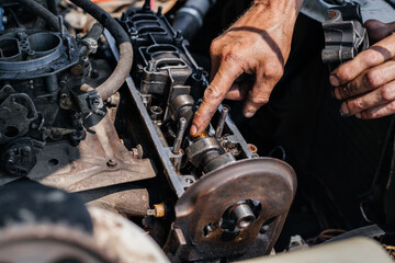 Fototapeta premium A worker repairs the cylinder head of an automobile engine. Oil removal valve. Car repairs. Car service