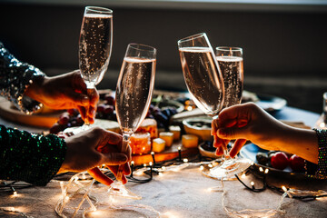 Friends celebrating Christmas or New Year eve party with champagne or sparkling wine.