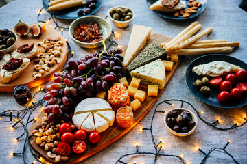 Wooden board with different kinds of cheese and appetizers served for dinner or aperitivo party.