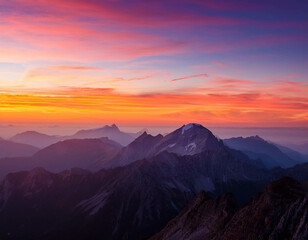 Obraz premium A breathtaking view of a mountain range at sunset, with the sky painted in shades of orange,