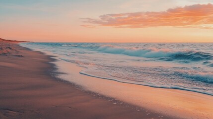 Obraz premium A sandy beach at sunset, with the sky ablaze in orange and pink hues, and waves gently lapping the shore.