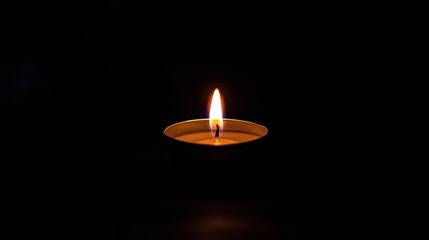A single candle burning brightly in the dark, casting a warm, flickering glow in an otherwise pitch-black room.